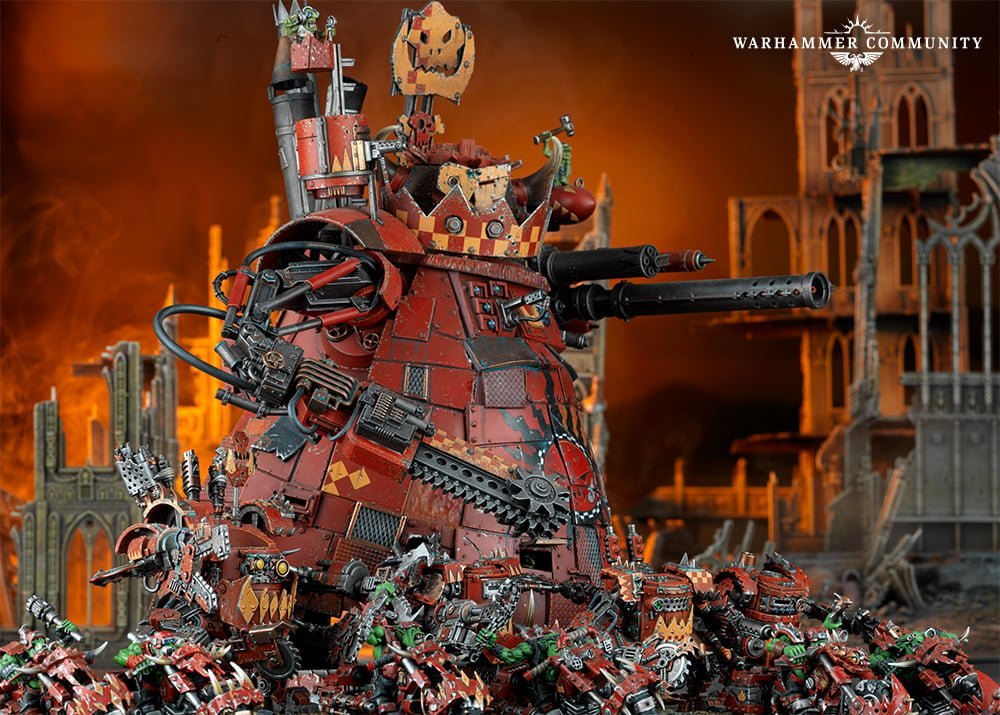 A red Ork Stompa towering over a mob of Ork Boyz in burning ruins